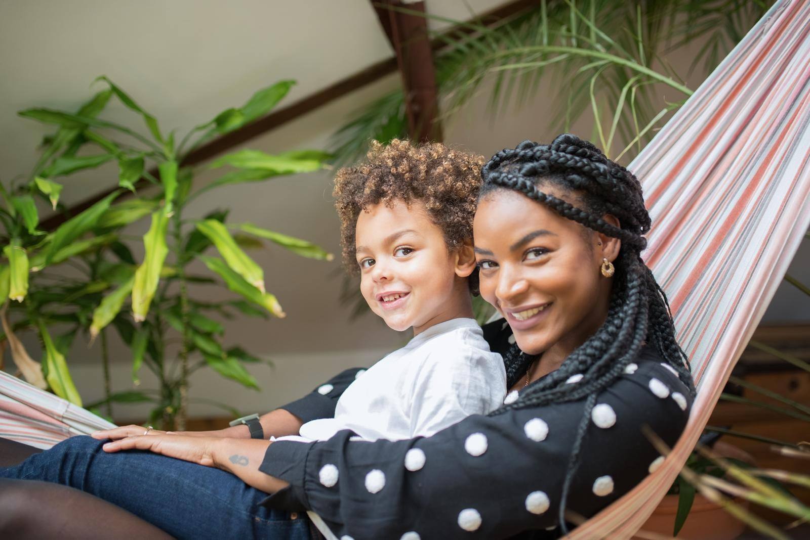 A carer and a young boy relaxing together in a hammock at home